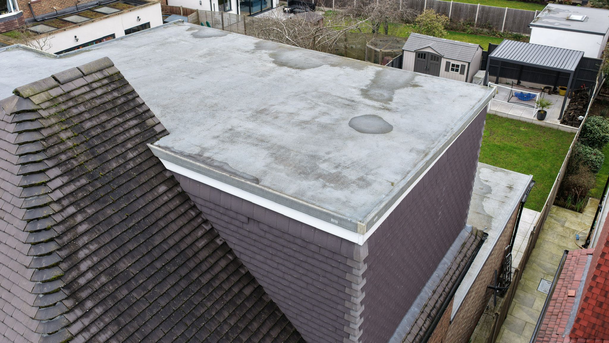 Aerial drone inspection of flat roof extension showing standing water